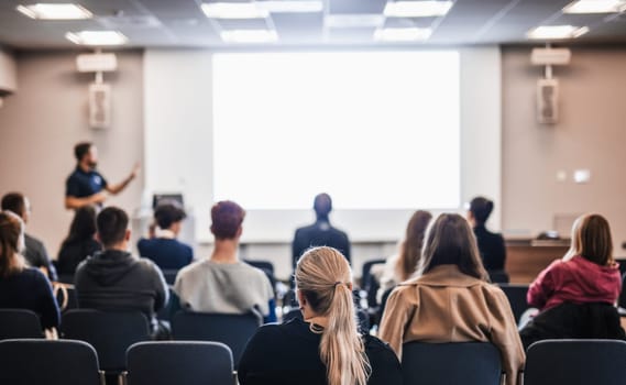 Speaker giving a talk in conference hall at business event. Rear view of unrecognizable people in audience at the conference hall. Business and entrepreneurship concept