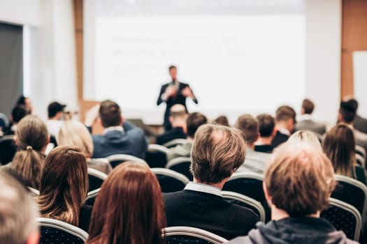 Speaker giving a talk in conference hall at business event. Rear view of unrecognizable people in audience at the conference hall. Business and entrepreneurship concept