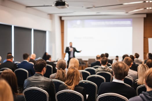 Speaker giving a talk in conference hall at business event. Rear view of unrecognizable people in audience at the conference hall. Business and entrepreneurship concept