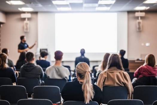 Speaker giving a talk in conference hall at business event. Rear view of unrecognizable people in audience at the conference hall. Business and entrepreneurship concept