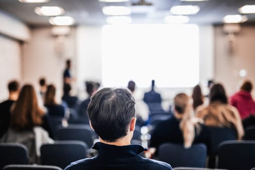 Speaker giving a talk in conference hall at business event. Rear view of unrecognizable people in audience at the conference hall. Business and entrepreneurship concept