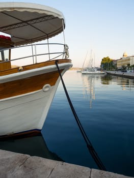 Sailing ships moored in the waterfront marina of Šibenik, Croatia at sunset