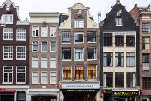 Amsterdam, Netherlands - April 21, 2023: Typical gabled houses on Damrak street in Amsterdam, Holland, Netherlands