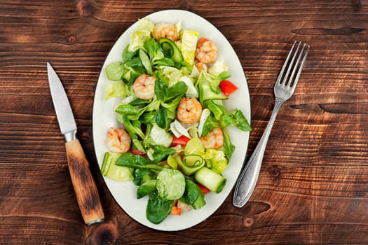 Plate with appetizing shrimps salad with green lettuce. Salad of shrimp or prawns. Healthy eating.