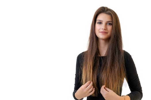 Beautiful smiling girl holding her long hair is posing on the light background. Horizontally.