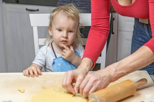 Thinking cute little child boy helps in baking Christmas cookies. Horizontally.