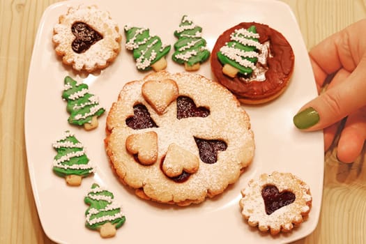 A woman offers Christmas cookies on a white plate