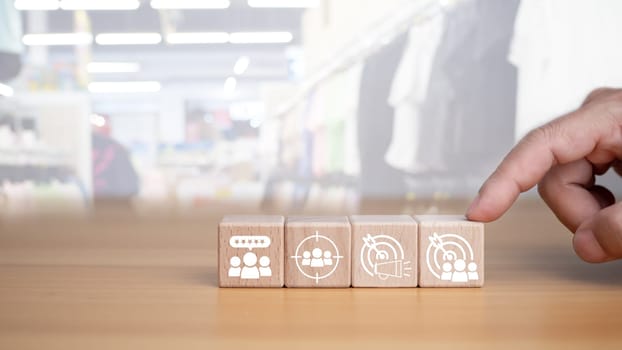 Human hands hold target customer icons on circle wooden planks. Placed on a wooden background, it represents selected business goals, target customers, marketing plans and strategies including customer-centric strategies.