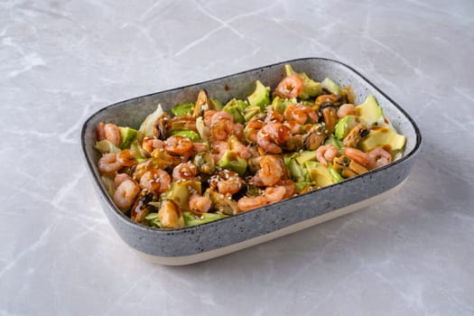Bowl with iceberg lettuce salad with shrimp, mussels and avocado