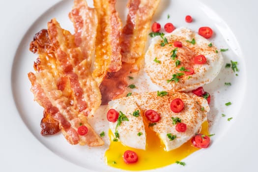 Portion of chili poached eggs with crispy bacon