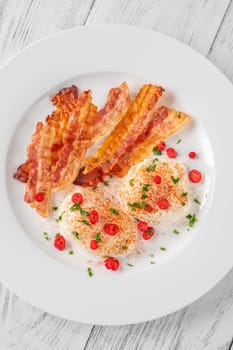 Portion of chili poached eggs with crispy bacon