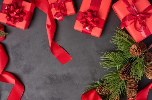 Christmas gifts and fir branch with pine cones on a black background, top view