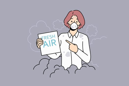 Woman suffers from air pollution and shows paper with inscription fresh air standing in protective mask. Problem of environmental pollution due to coal plants and carbon emissions.