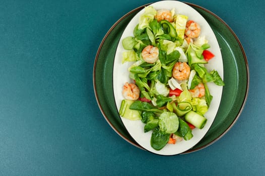 Plate with salad of fresh vegetables, mixed greens and shrimp.