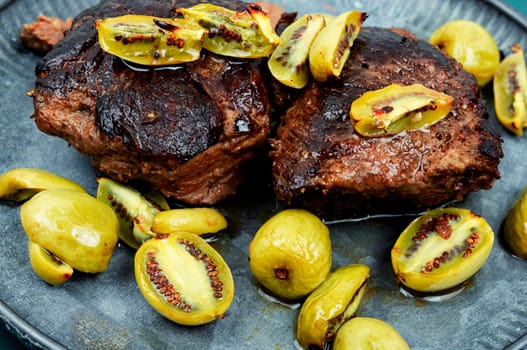 Roasted ostrich steak and mini kiwi on a plate