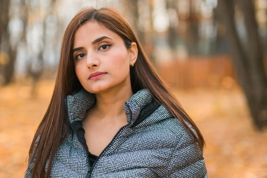 Beautiful indian woman generation z relaxing and feeling nature at autumn park in fall season. Diversity and gen z youth.