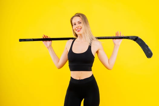 Ice hockey fan female in sports wear with hockey stick in a studio