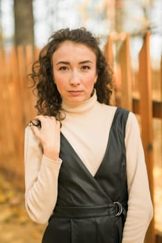 Autumn portrait of a beautiful happy curly woman in fall season. Millennial generation female. Natural beauty