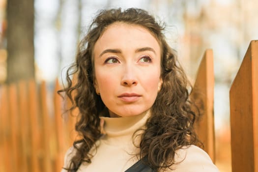 Autumn portrait of a beautiful happy curly woman in fall season. Millennial generation female. Natural beauty