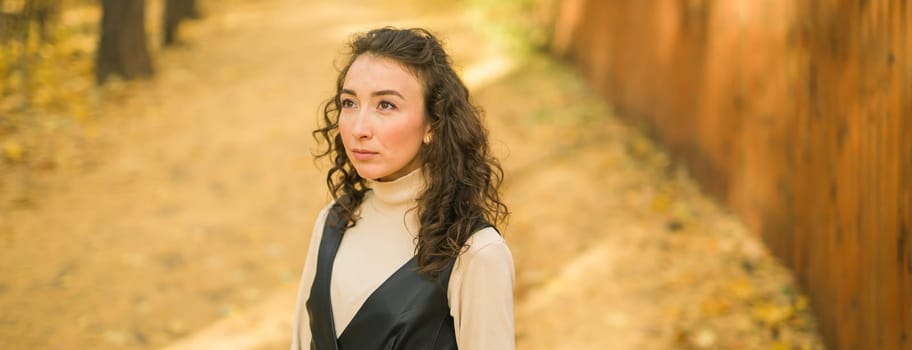 Autumn portrait of a beautiful happy curly woman in fall season. Millennial generation female. Natural beauty