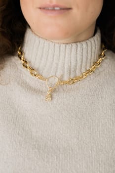 Close-up female in modern gold metal necklace chain with gold bunny pendant.