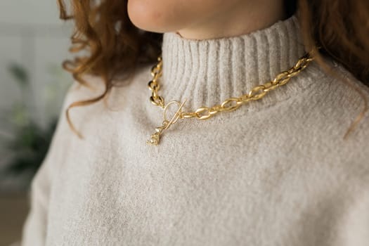 Close-up female in modern gold metal necklace chain with gold bunny pendant.