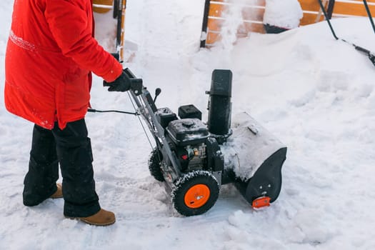 A man clear snow from backyard with snow blower. Winter season and snow blower equipment.
