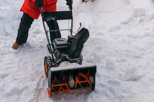 A man clear snow from backyard with snow blower. Winter season and snow blower equipment.