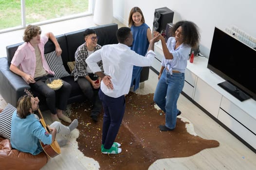 Diversity group of friends having party together at home. Happiness young people having fun dancing, playing guitar and singing in the living room. Top view image. Youth lifestyle concept
