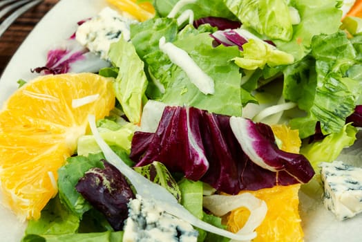 Raw salad with greens, oranges and cheese. Delicious healthy food