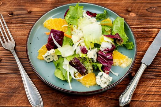Raw salad with greens, oranges and cheese. Delicious healthy food