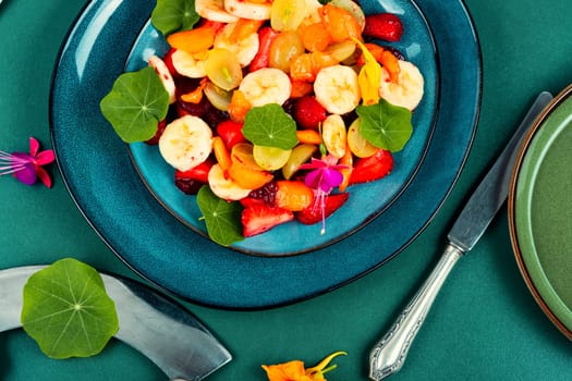 Vitamin fruit salad with banana, strawberries, grapes and nasturtium