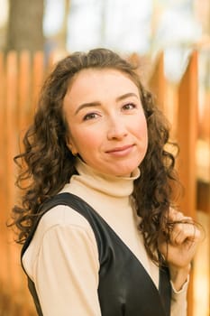 Autumn portrait of a beautiful happy curly woman in fall season. Millennial generation female. Natural beauty