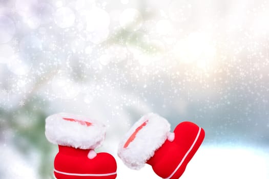 A pair of red Christmas boots or Santa Claus boots over an abstract snowy winter Landscape with snowflakes and stars. Saint Nicholas boots.Copy space. Card design.