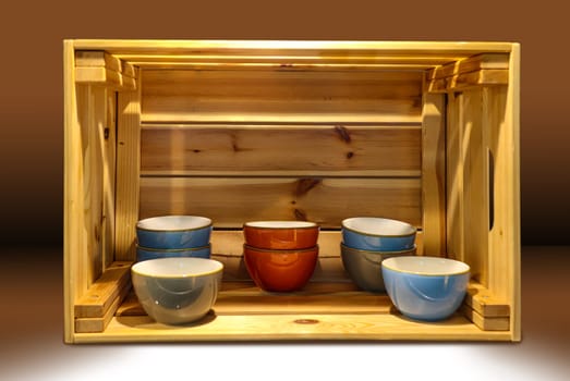 Several ceramic bowls stand very decoratively in a wooden box.