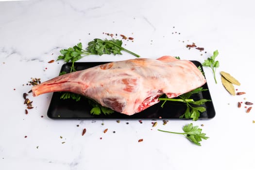 Raw lamb shoulder ready for cooking with garlic, rosemary. Black background. Top view