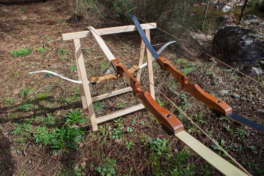 Wooden bows displayed over folding sawhorses. Forest background