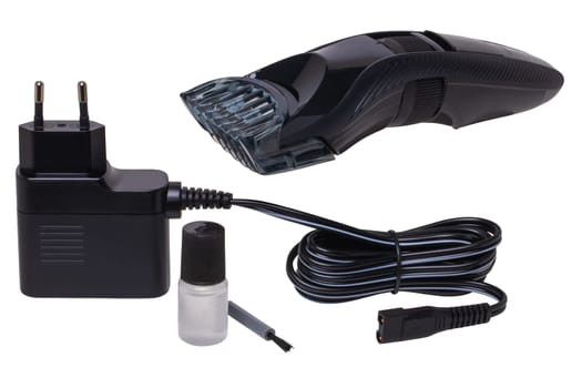 Close-up of a new black and silver rechargeable beard and hair clipper with power supply, brush and oil isolated on white. Cordless hair and beard trimmer. Macro.