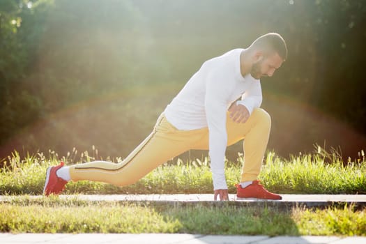 The sporty young man is stretching and doing relaxing exercise outdoors.
