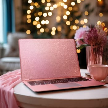 beautiful pink laptop on the table with flowers on the background of festive illuminations .Concept for gifts and holidays.