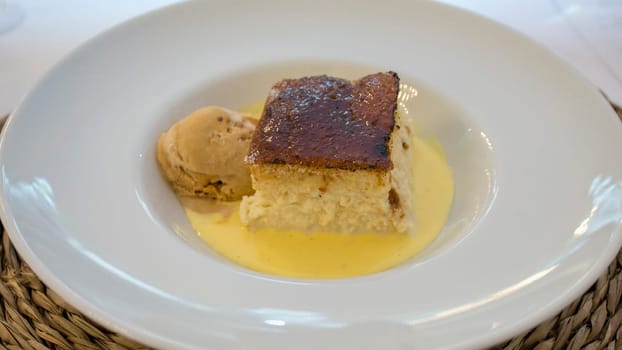 Wet brioche with scoop of vanilla ice cream. Plate served over rattan mat
