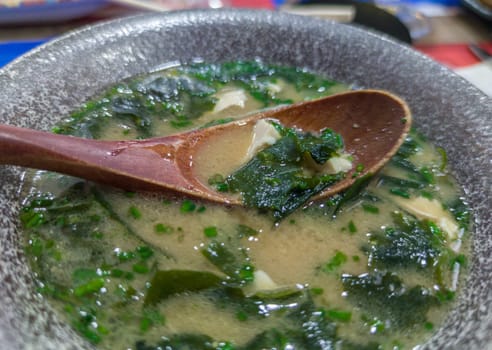 Miso soup with seaweed and tofu. Wooden spoon on grey bowl