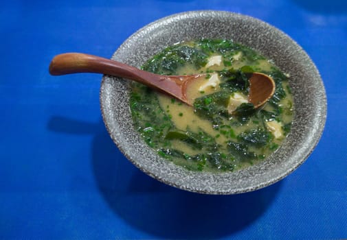 Miso soup with seaweed and tofu. Wooden spoon on grey bowl