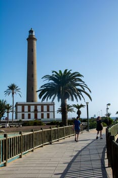 Lighthouse in Maspalomas ( Faro de Maspalomas ) on the Canary Island of Gran Canaria in Spain with palm tree