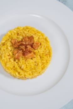 Portion of saffron risotto garnished with pancetta