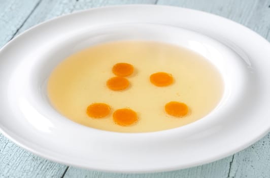 Portion of clear chicken broth in white plate