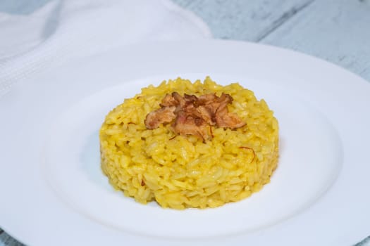 Portion of saffron risotto garnished with pancetta