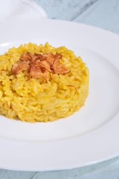 Portion of saffron risotto garnished with pancetta