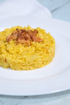 Portion of saffron risotto garnished with pancetta