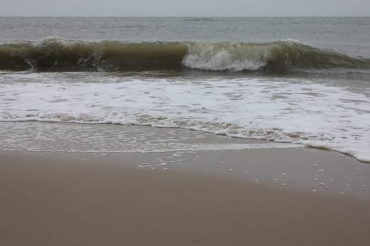 Waves with white crests inundate the sandy beach